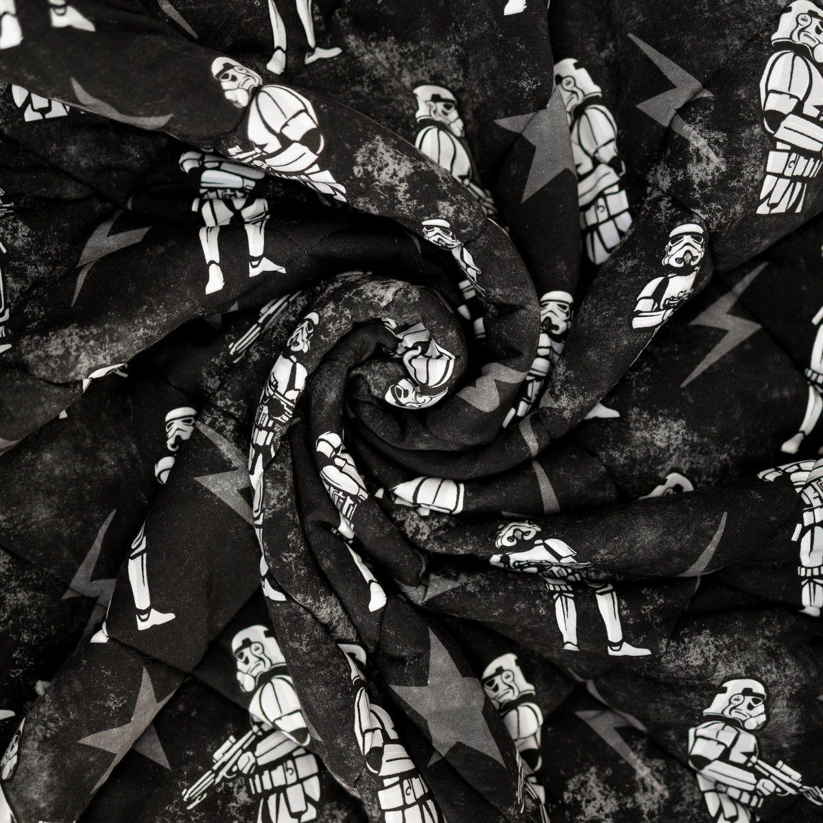 A black and white quilted blanket featuring a repeating pattern of Stormtroopers and stars.