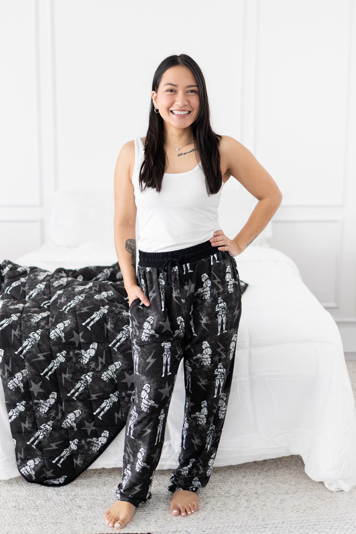 A woman stands in front of a bed wearing pajamas with a Stormtrooper print.