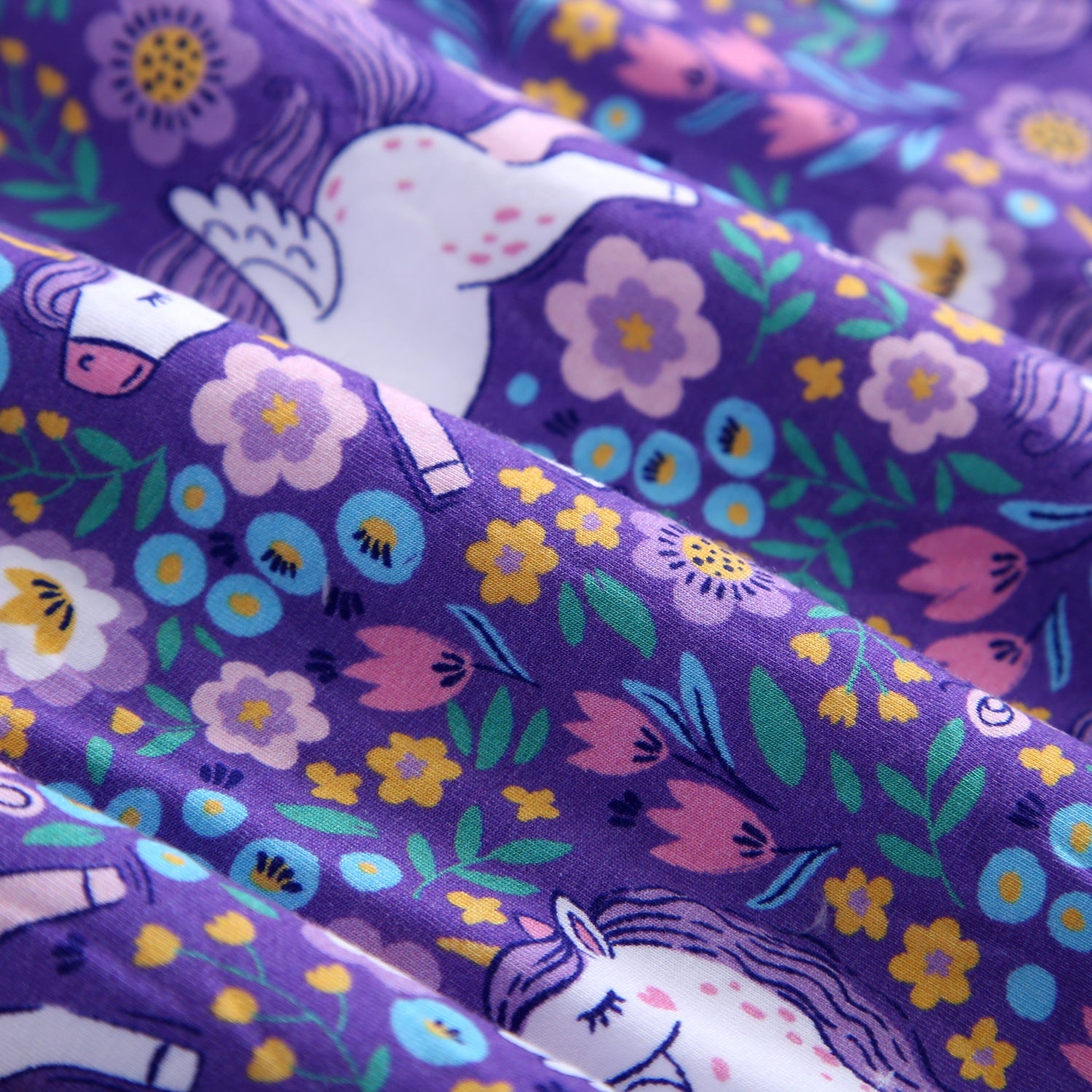 Purple fabric with a unicorn and floral print.