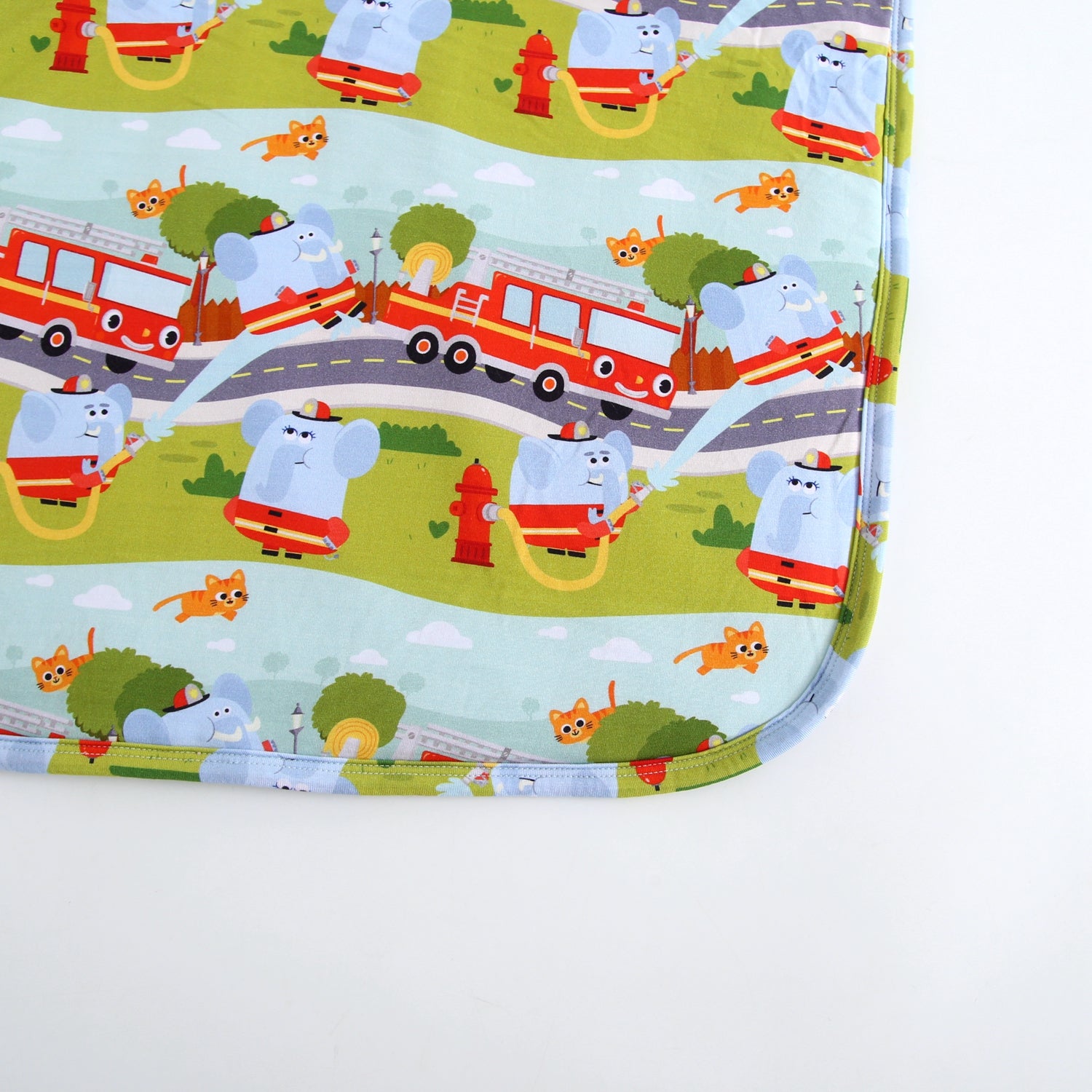A plush blanket with a fire truck and elephant pattern.