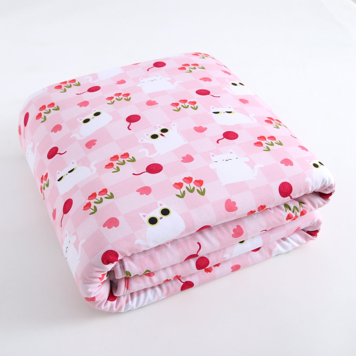 A folded pink blanket with a checkered pattern and white cats with sunglasses and flowers.