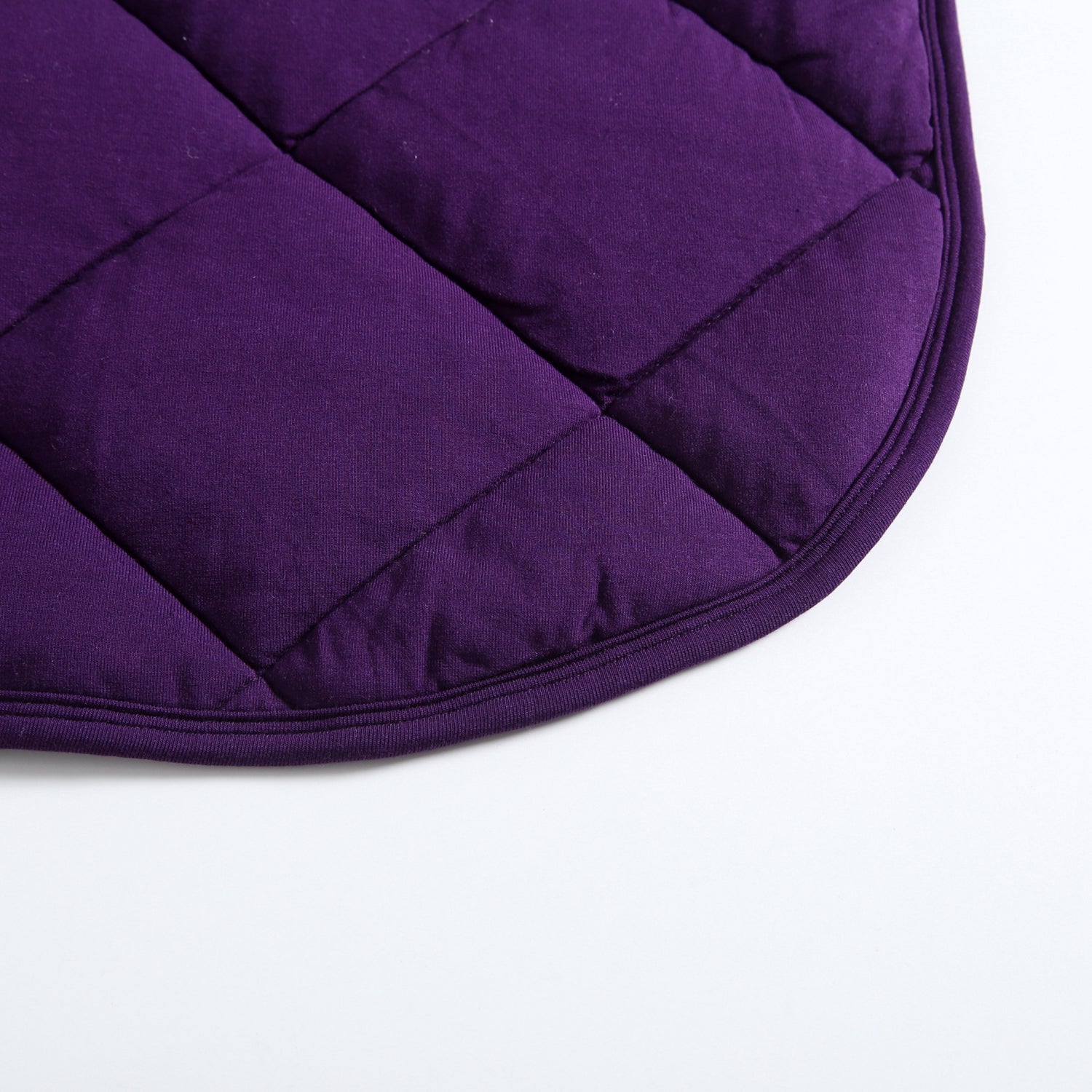 A close-up of a quilted purple bamboo fabric with a rounded edge.