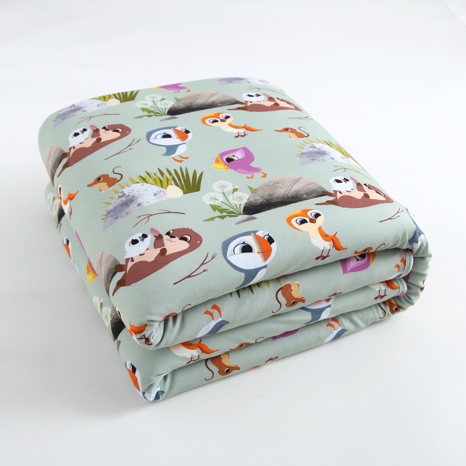 A folded plush blanket with a Puffin Rock™ pattern featuring cartoon animals and nature elements.