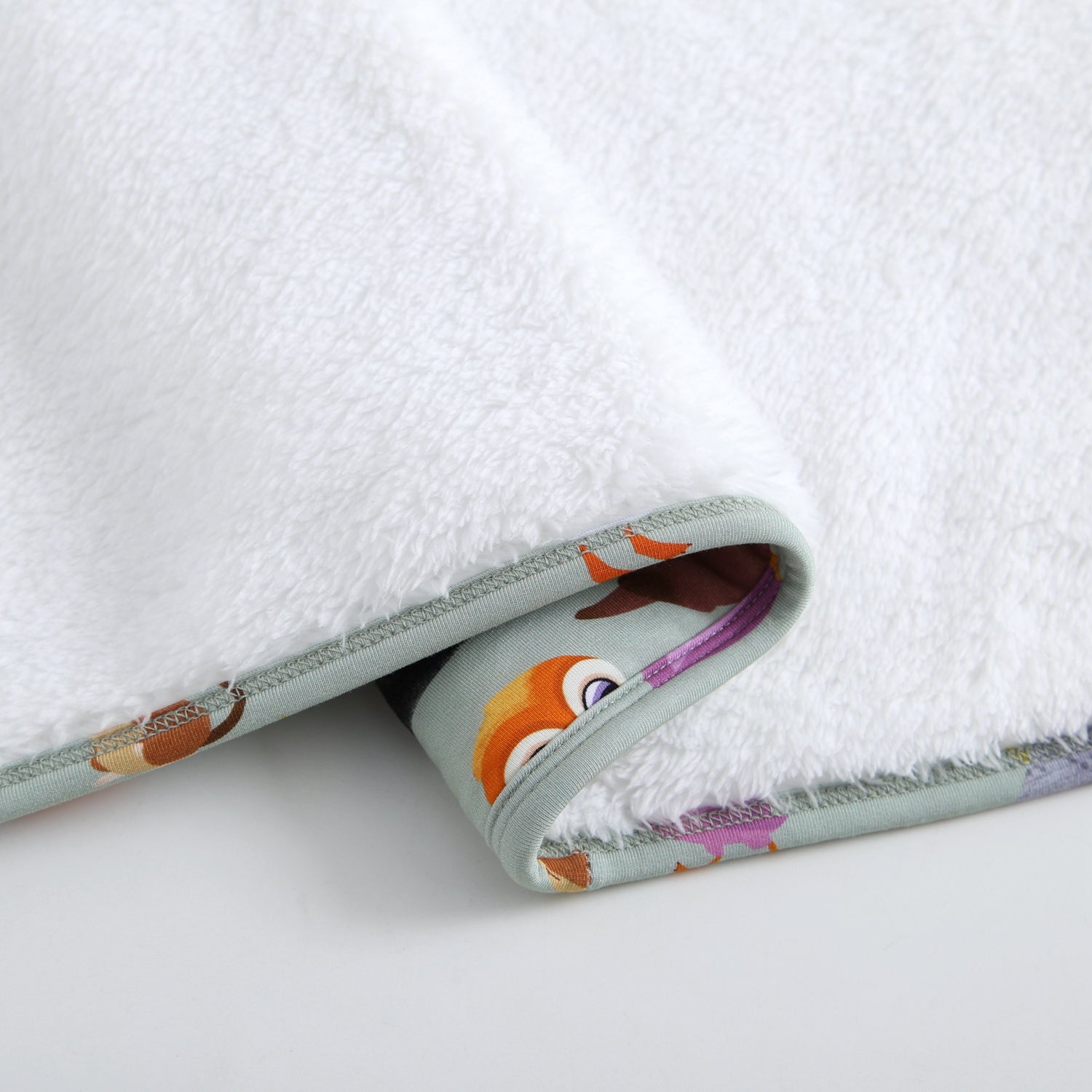 A white plush blanket with a patterned edge featuring cartoon puffins.
