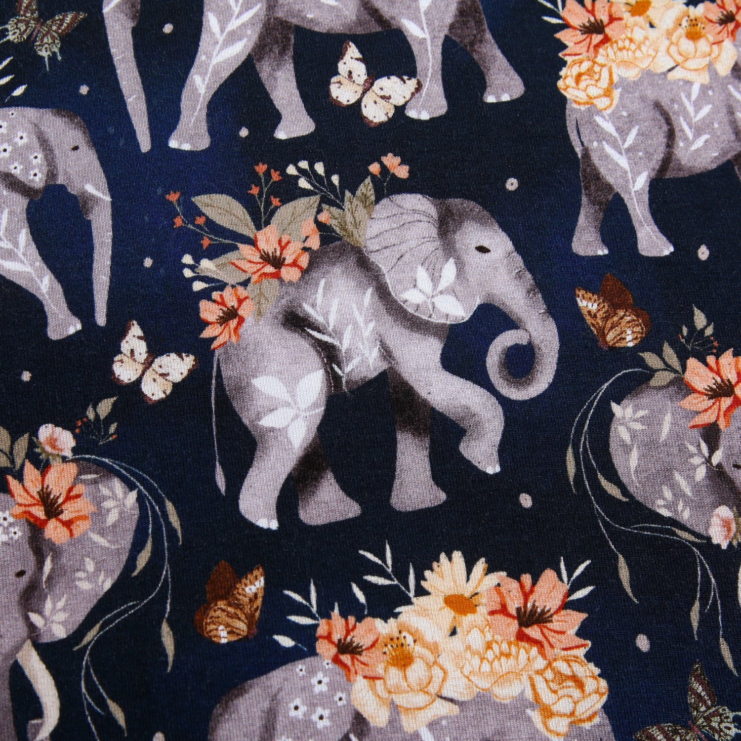 A dark blue blanket with a repeating pattern of grey elephants and orange and white flowers.