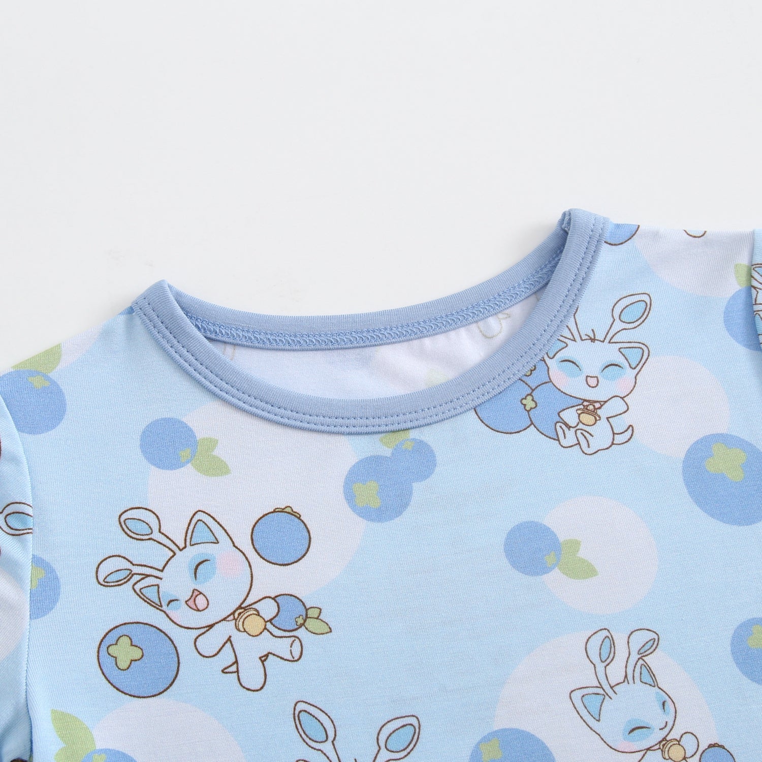 Light blue baby pajamas with a blueberry and cartoon cat print.