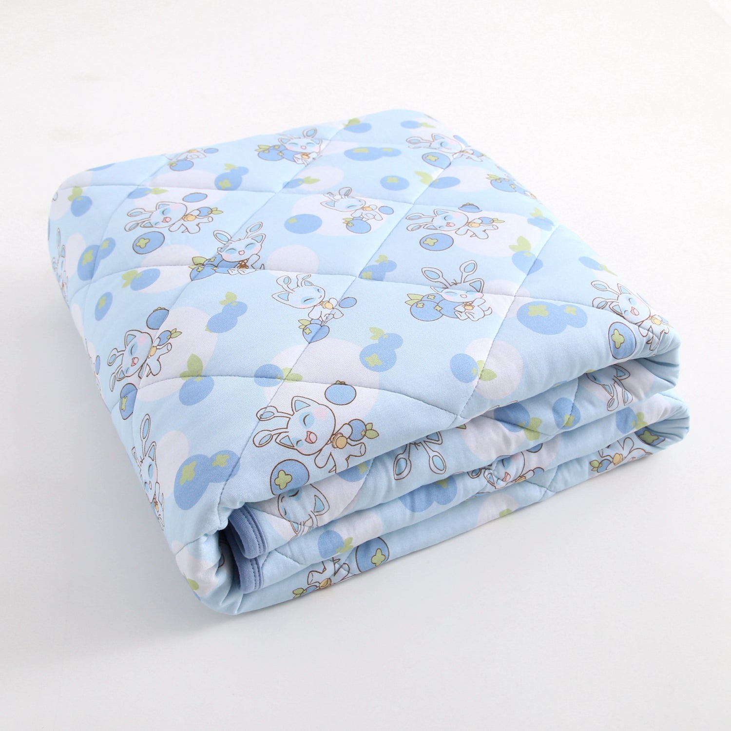A light blue quilted blanket with a pattern of cartoon animals and blueberries.