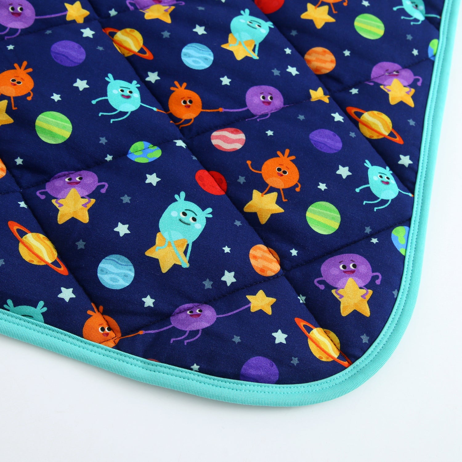 A quilted blanket with a dark blue space-themed print featuring cartoon planets and characters.