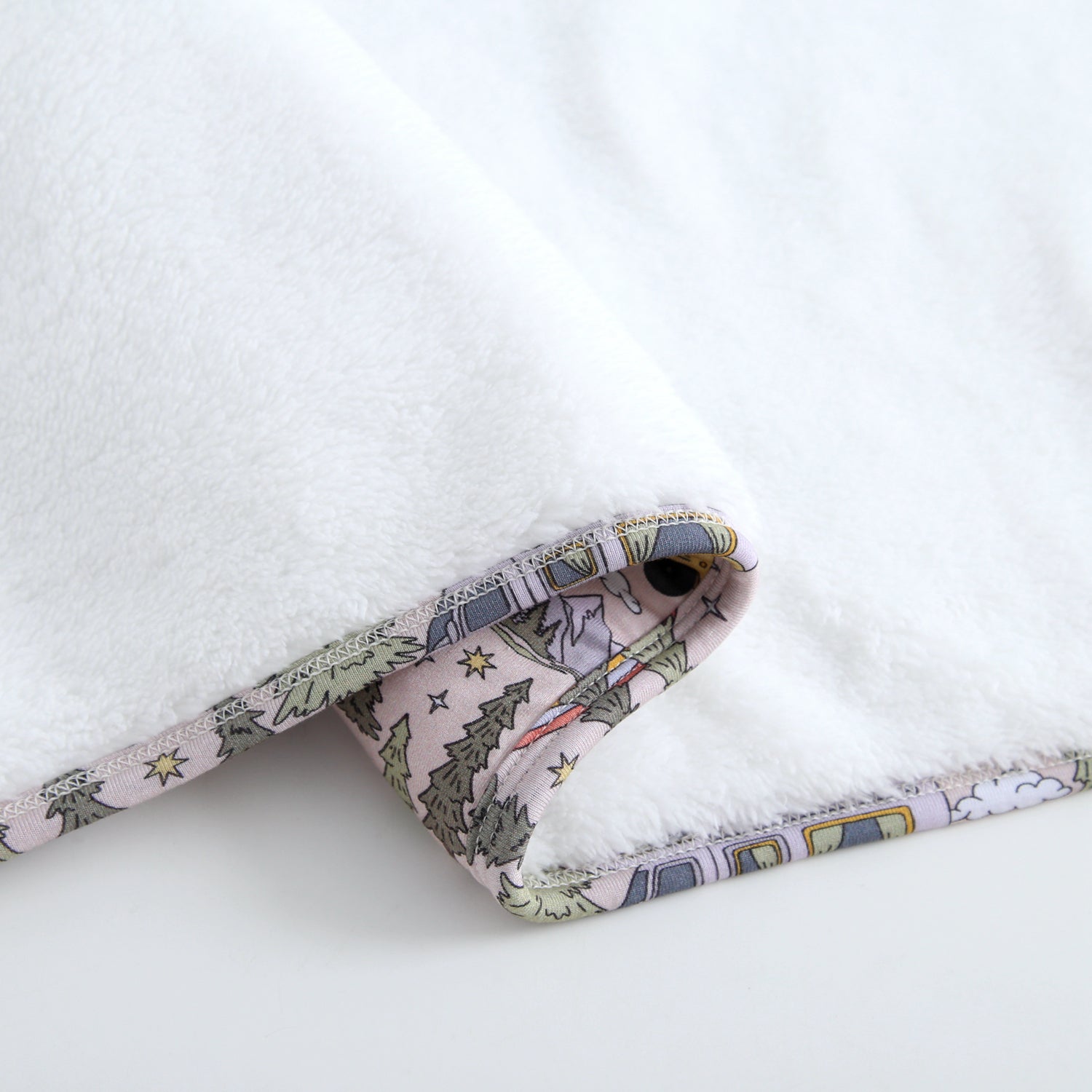 A white plush blanket with a vintage camper print trim.