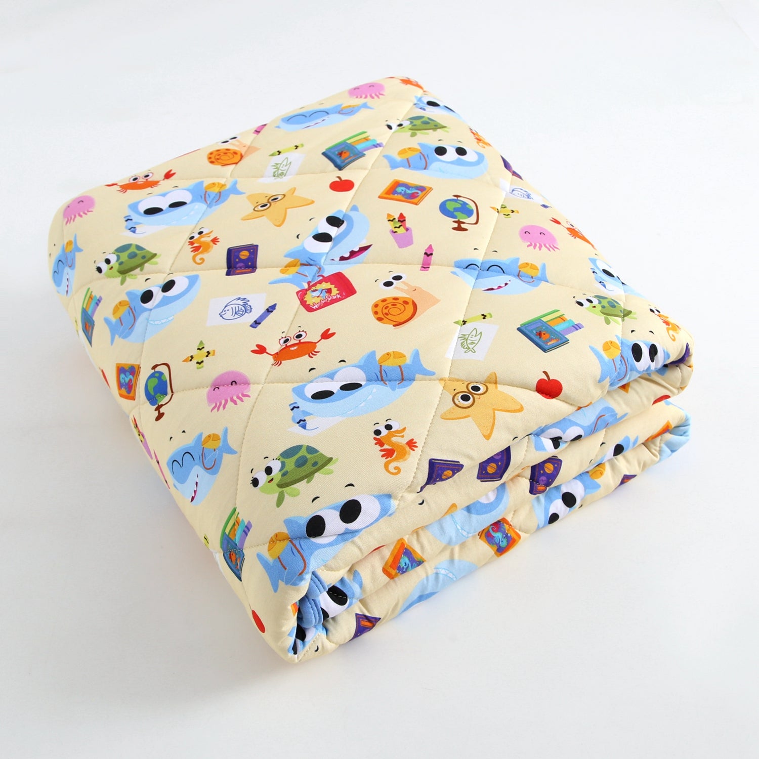 A folded yellow blanket with a pattern of cartoon sea creatures and school supplies.
