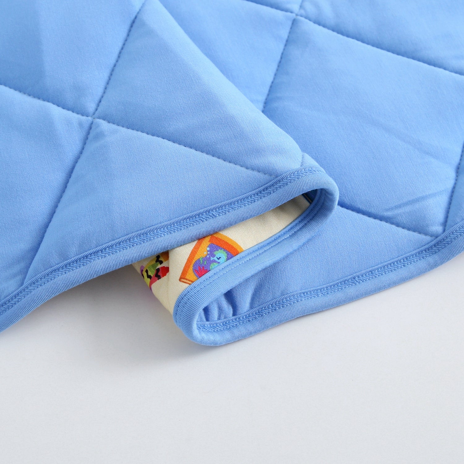 A light blue quilted blanket with a finny the shark pattern peeking out from the edge.