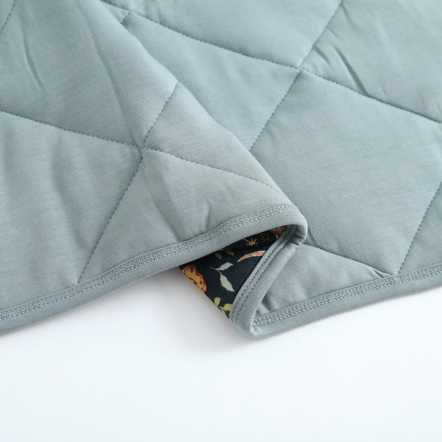 A quilted bamboo blanket with a diamond pattern and a floral print lining.
