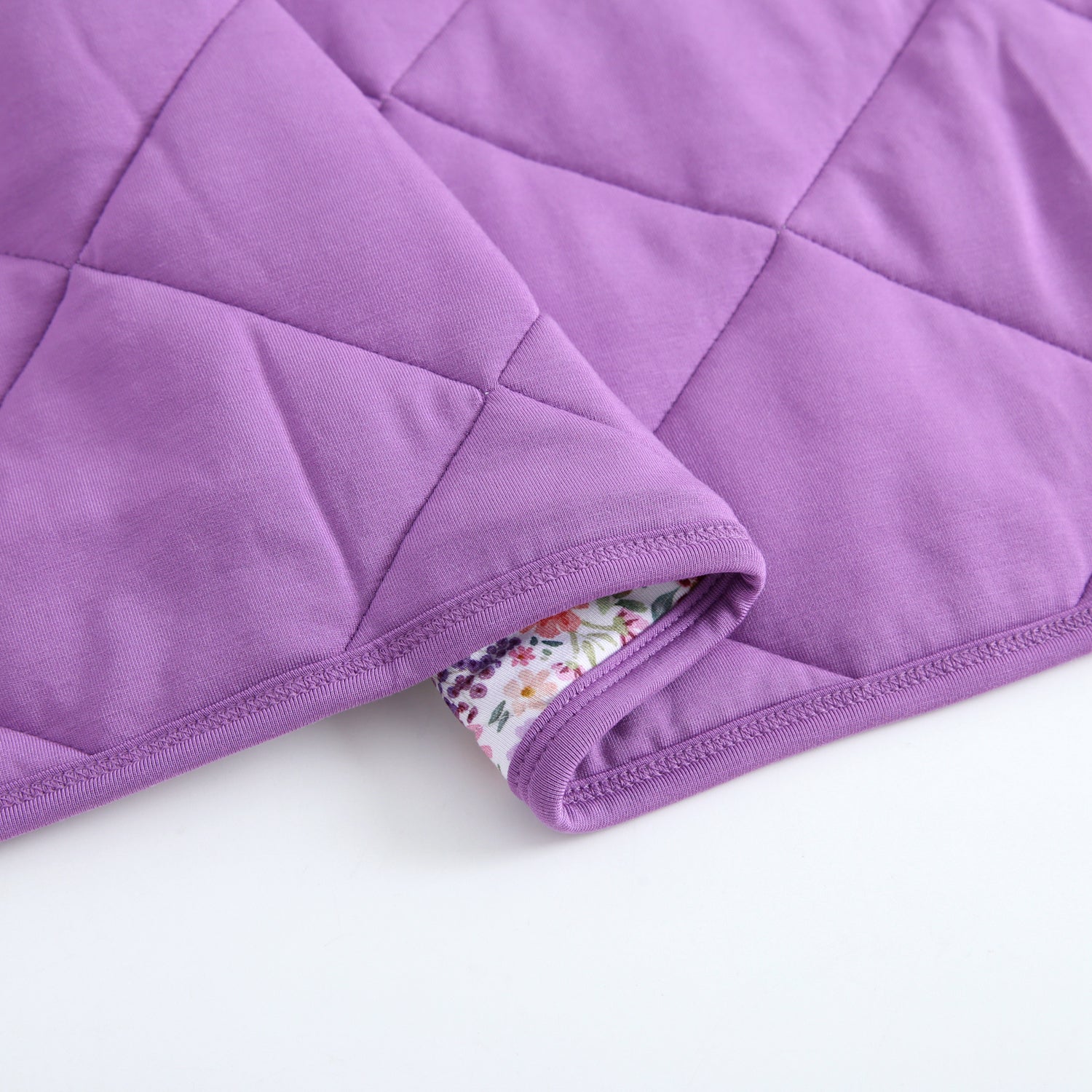 A quilted purple blanket with a floral lining.