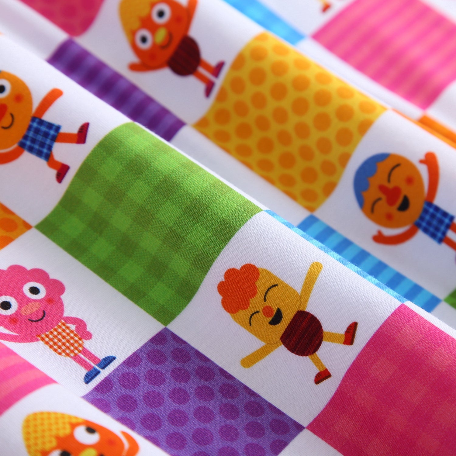 A white blanket with colorful squares featuring cartoon characters.