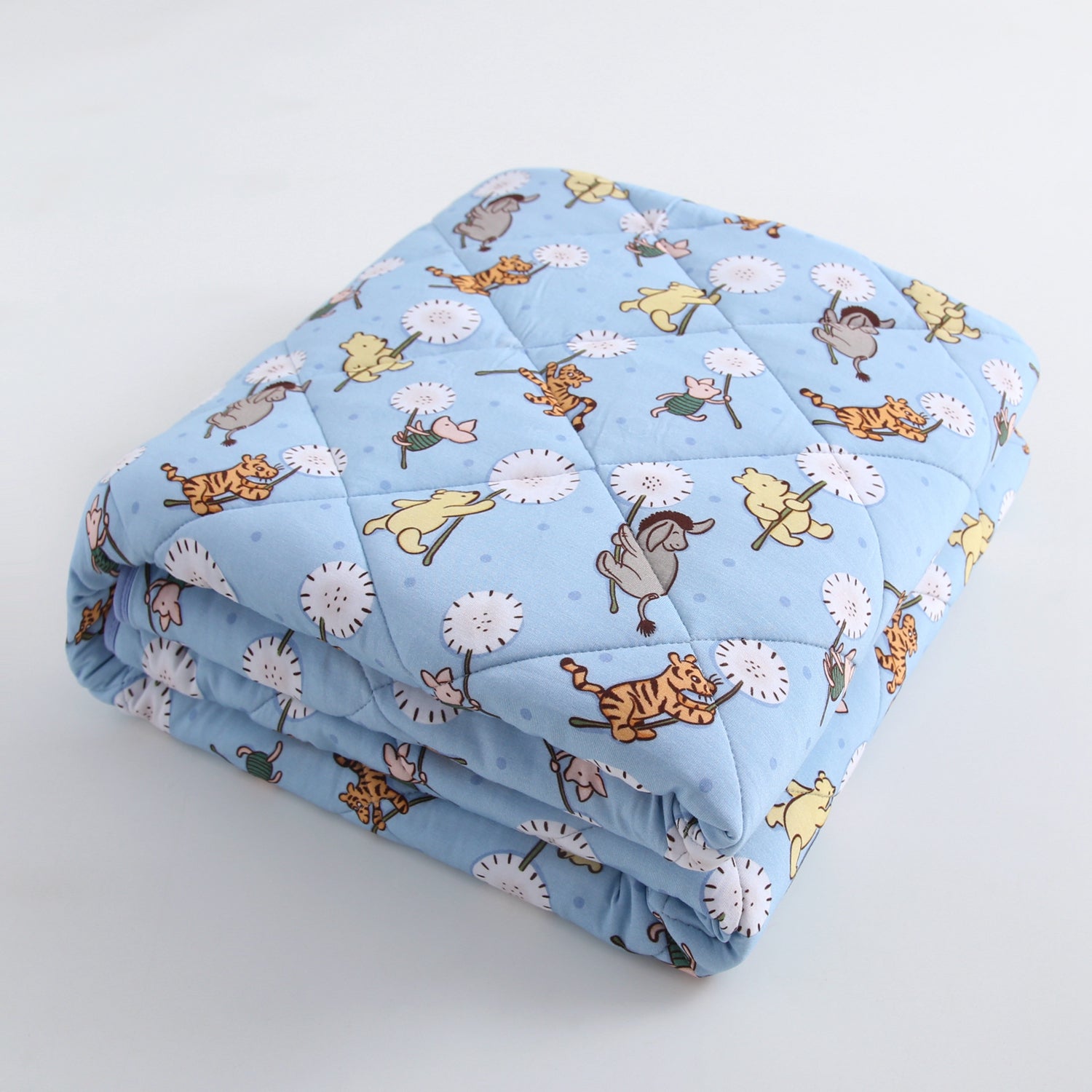 A light blue quilted blanket with a Winnie the Pooh and friends print.
