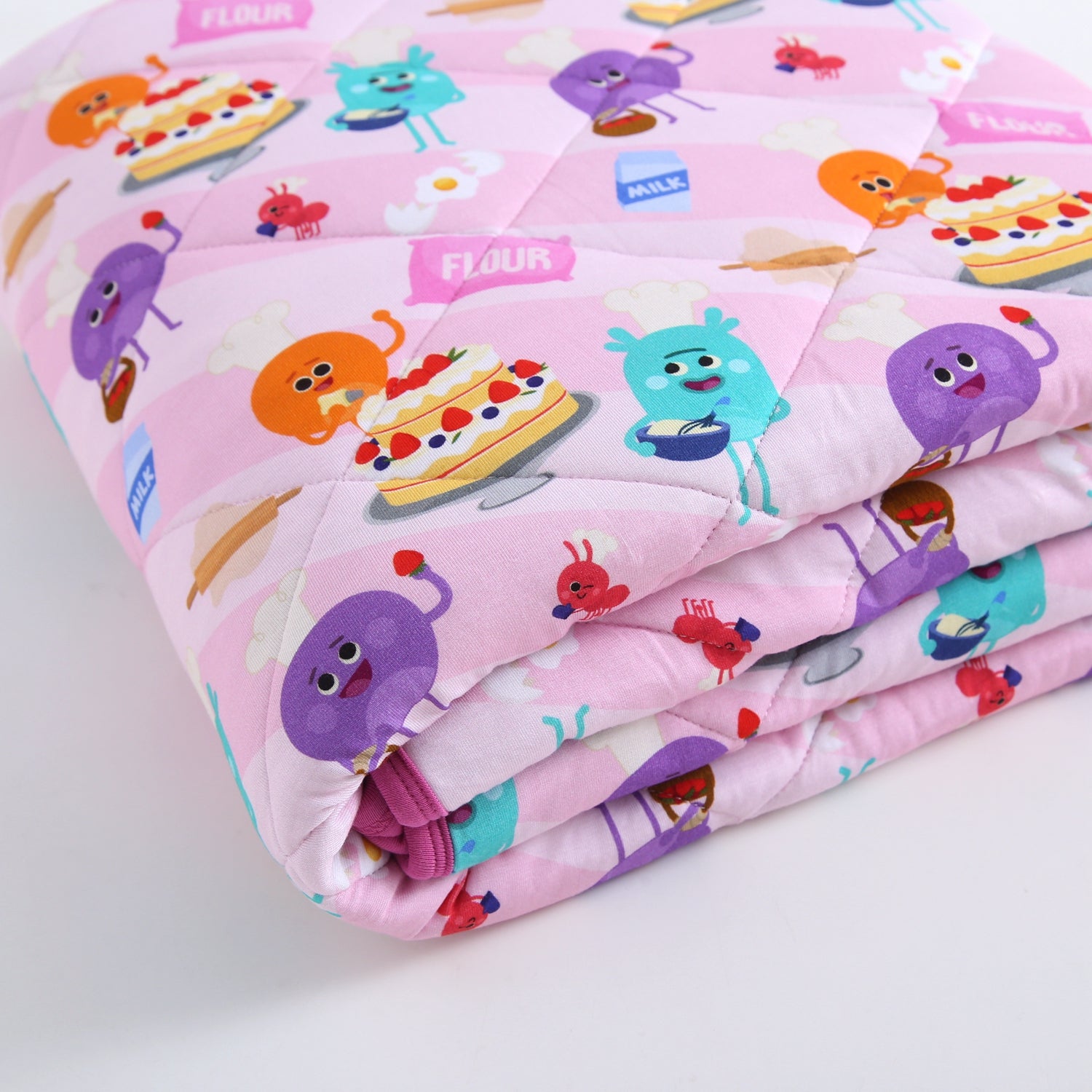 A pink quilted blanket with cartoon bakers and desserts.