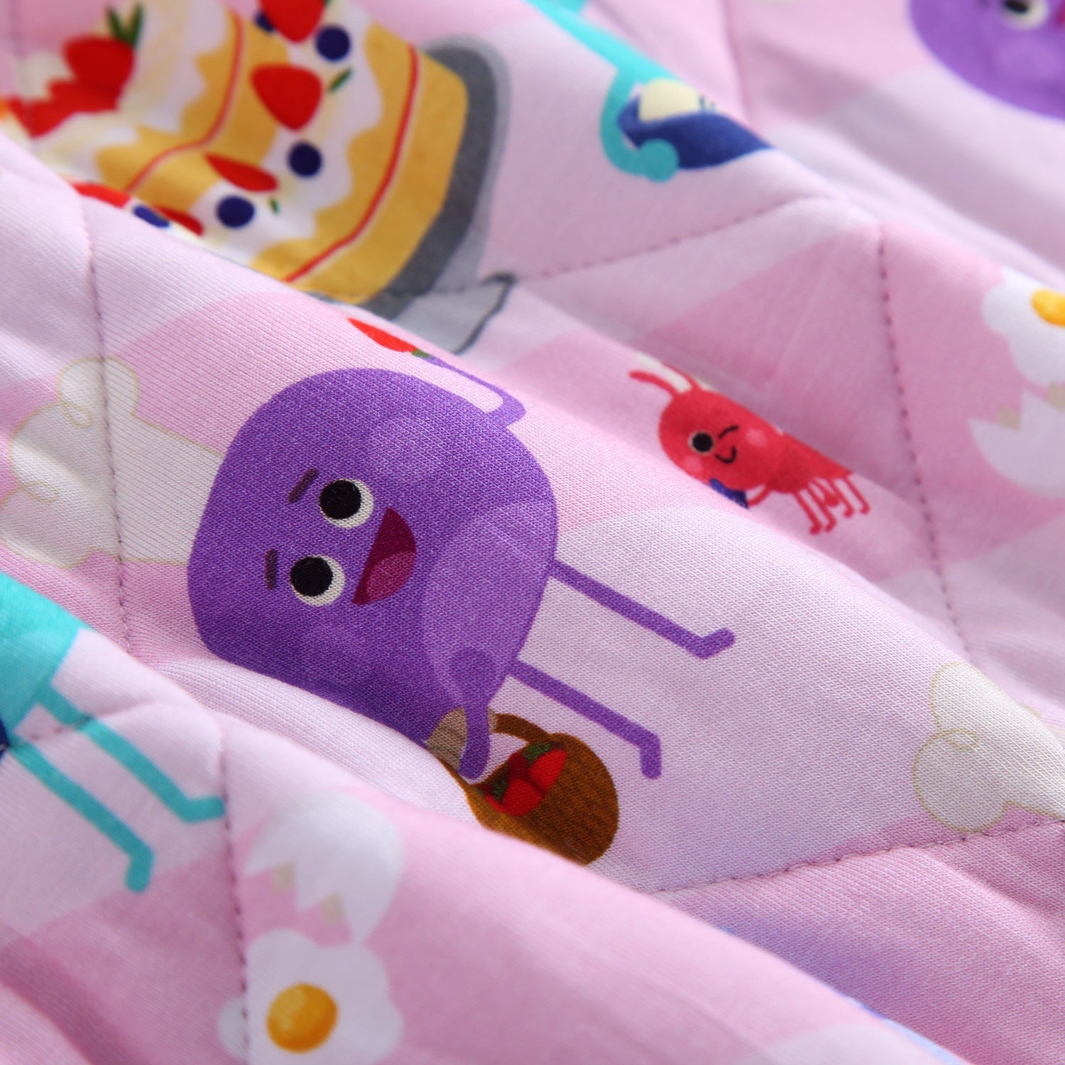 A pink quilted blanket with cartoon characters including a purple octopus and a red shrimp.