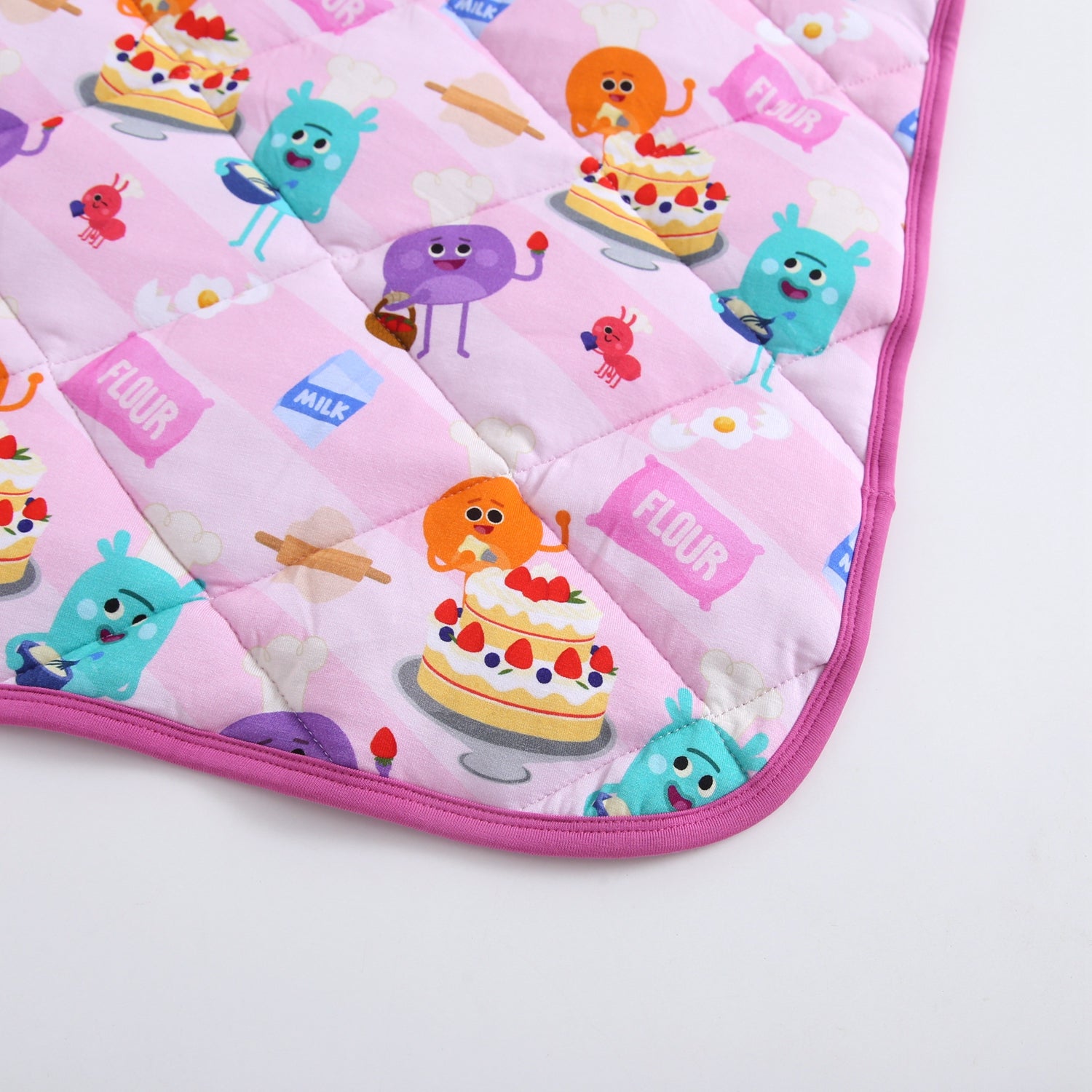 A pink quilted blanket with a baking-themed pattern featuring cartoon characters and cakes.