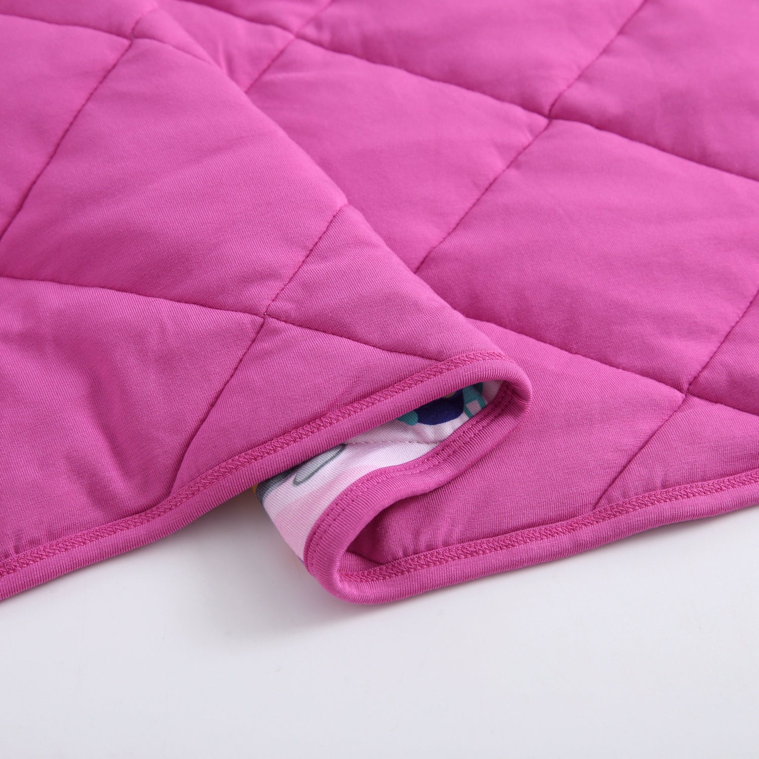 A pink quilted blanket with a patterned lining is shown.