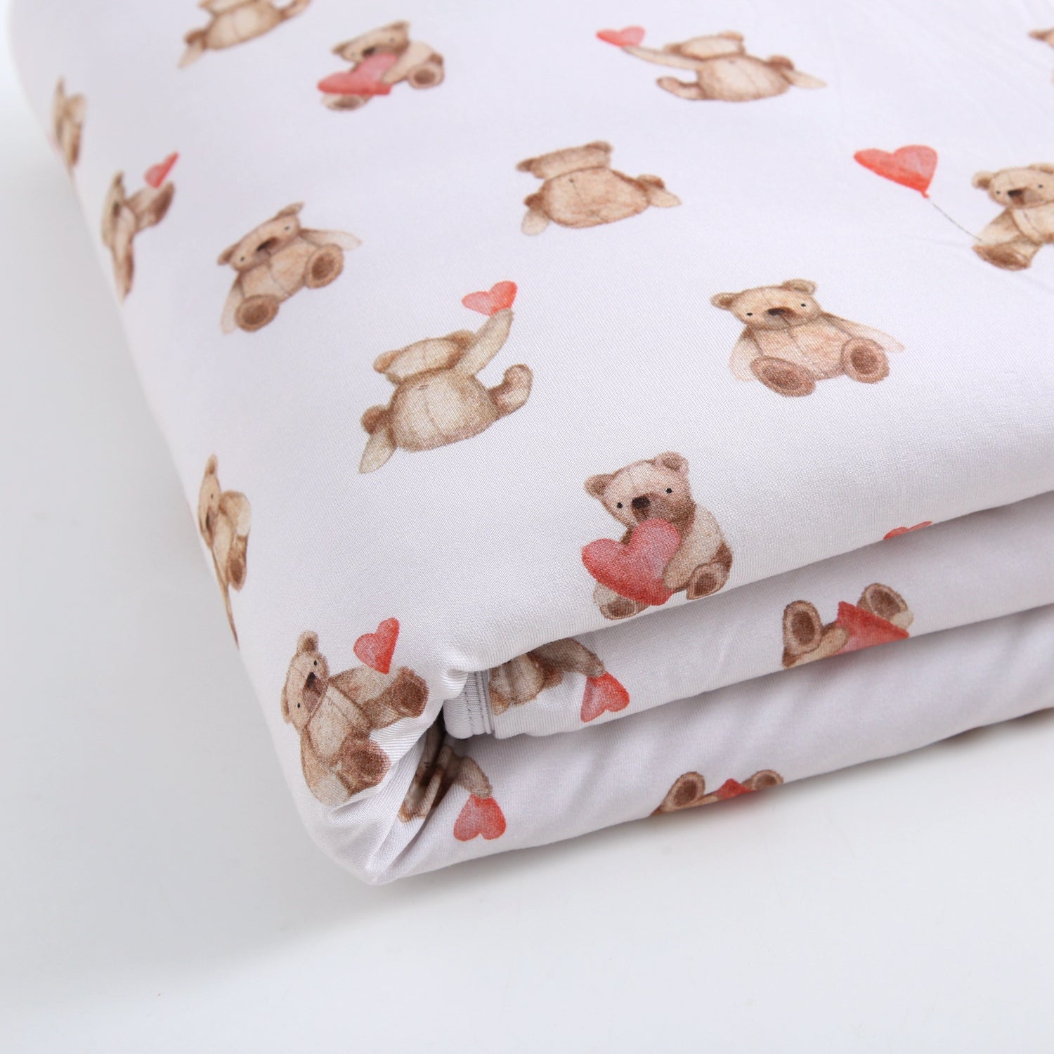 A white plush blanket with a watercolor pattern of teddy bears holding red hearts.