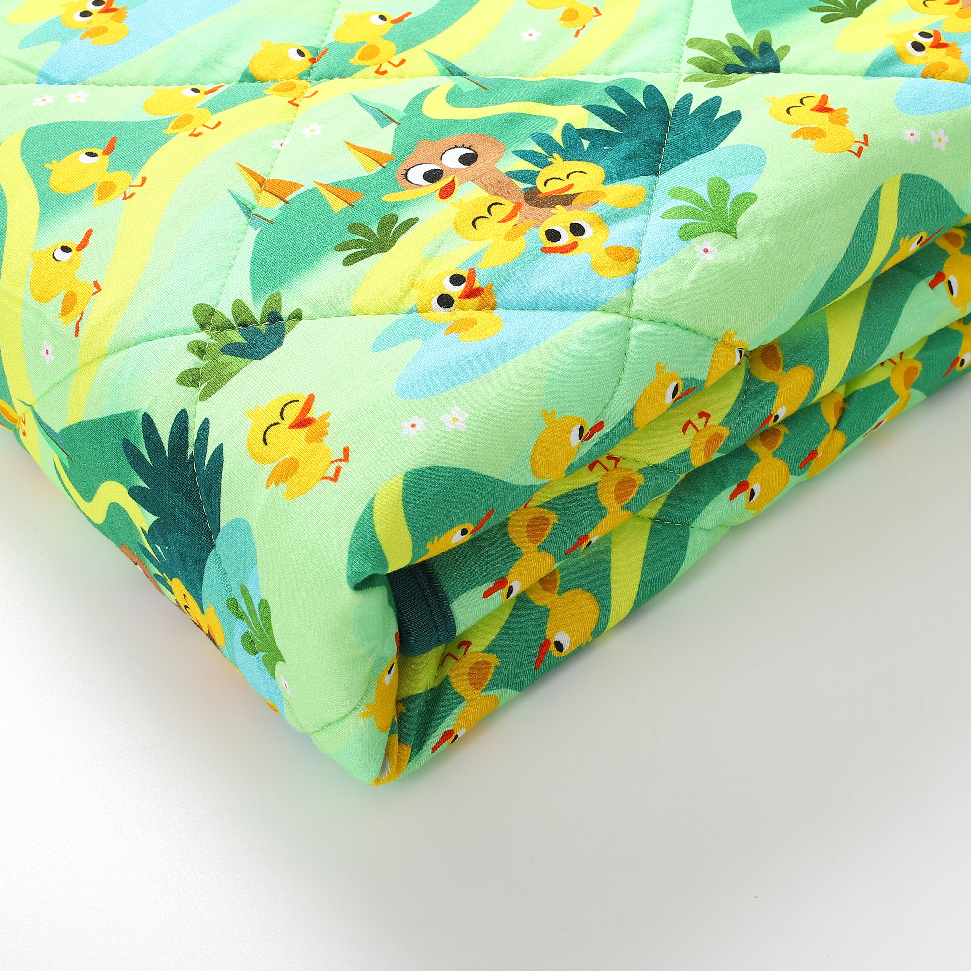 A quilted couch cover with a pattern of yellow ducklings and green foliage.