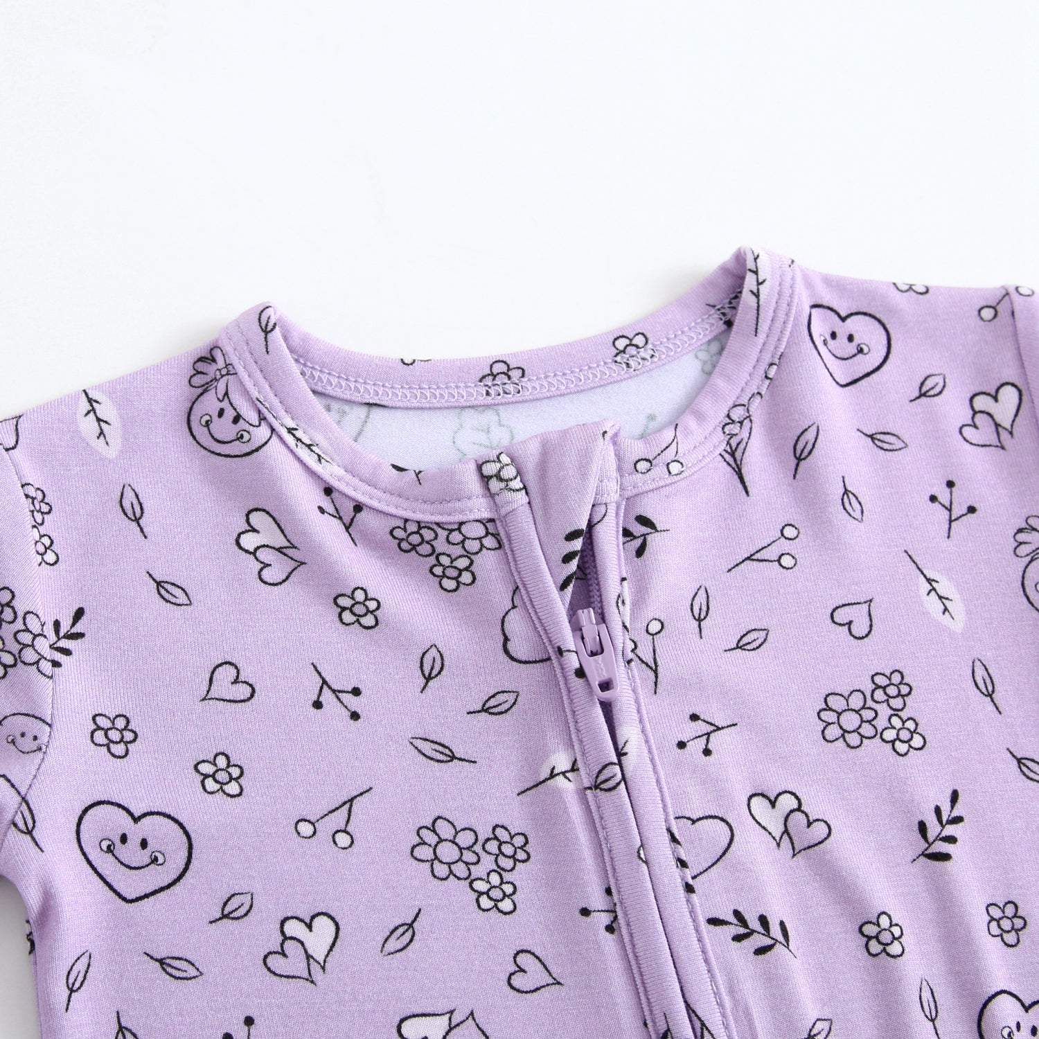 A lilac bamboo pajama set with a doodle print of smiley faces and flowers.