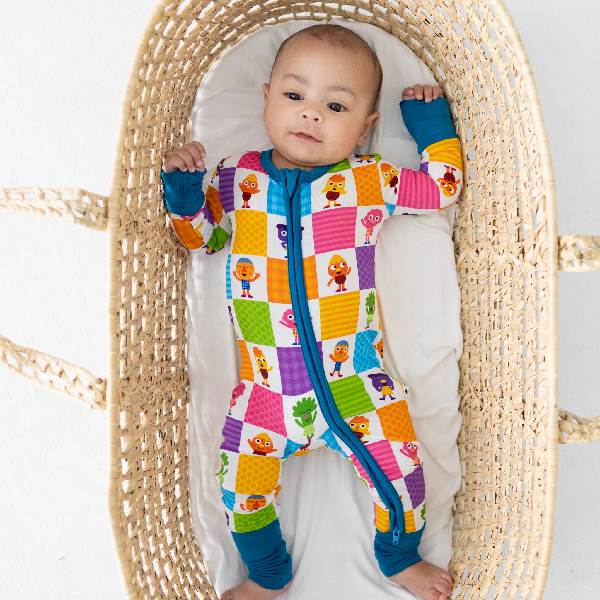 Baby in a colorful, patterned sleepsuit with cartoon characters.
