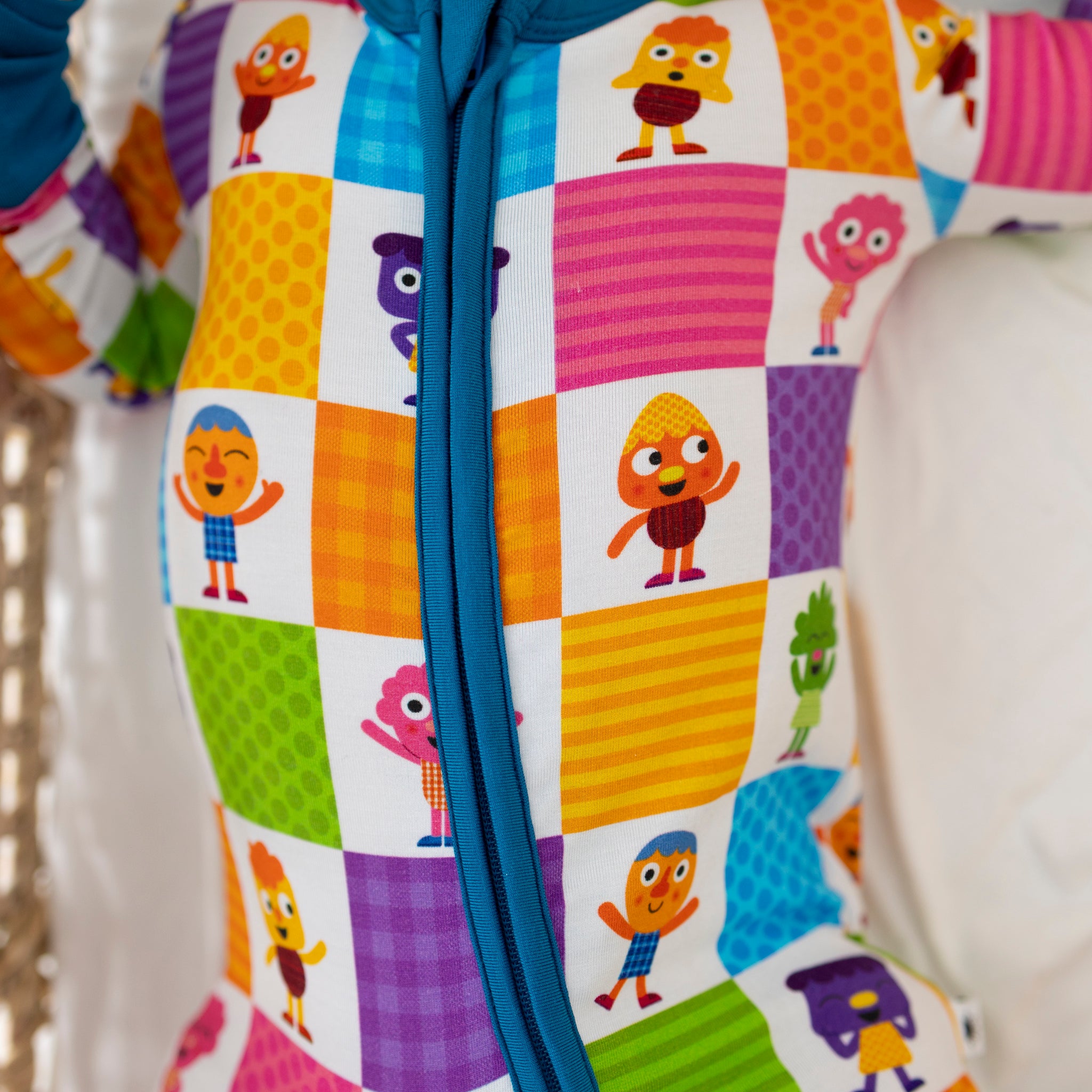 Close-up of a colorful zip-up pajama featuring a patchwork pattern of Noodle & Pals characters.
