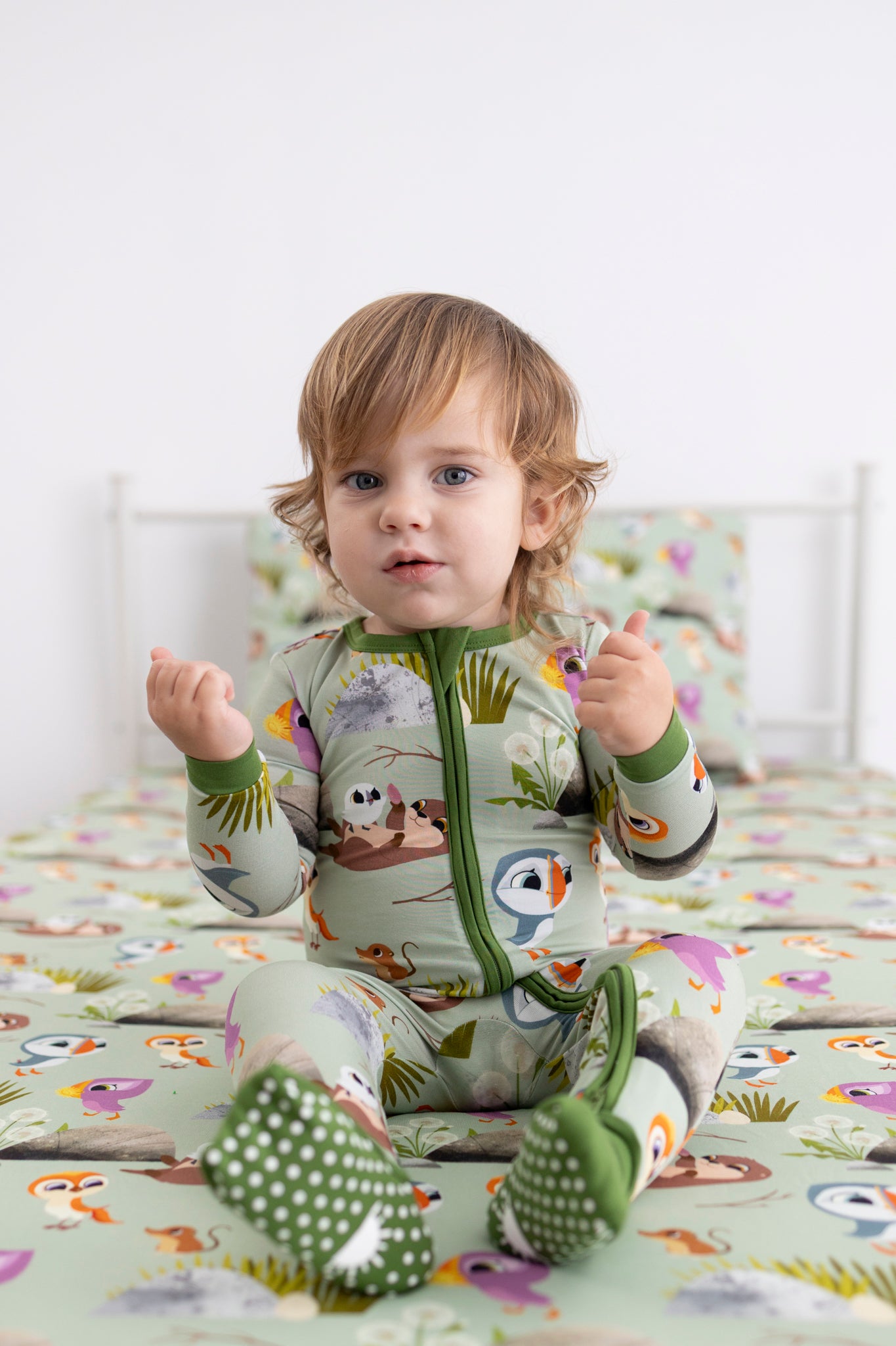 A baby wearing a green Puffin Rock™ Tencel™ Modal zip pajama set.