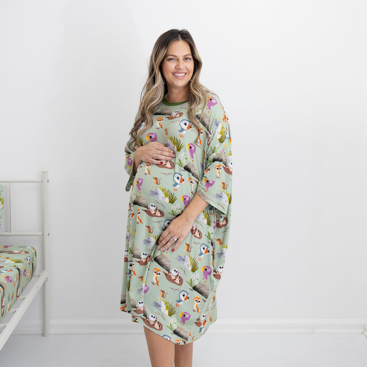 A pregnant woman wears a light green sleep tee with a Puffin Rock print.