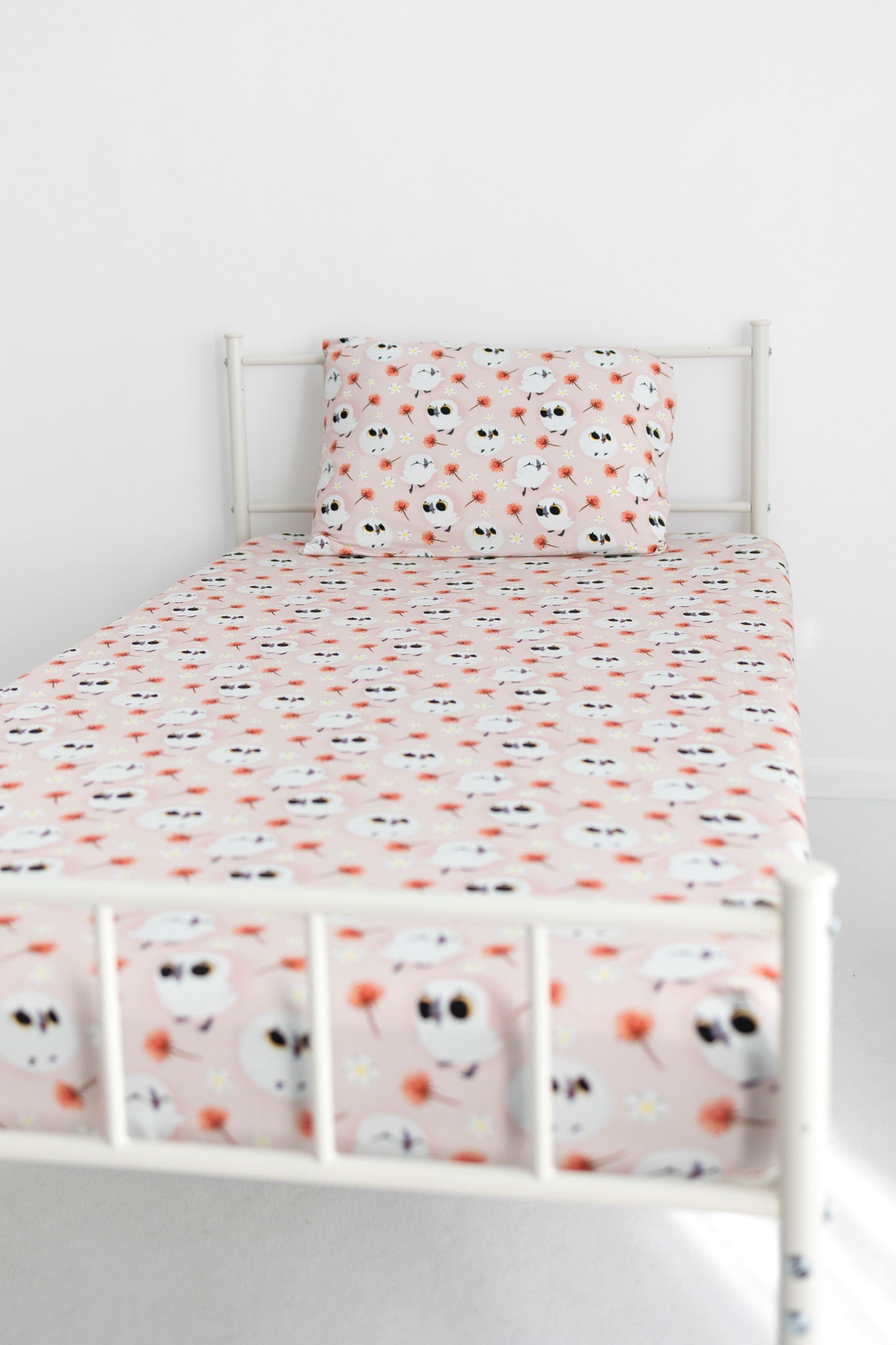 Twin sheet and pillow case set with a pink background and a pattern of puffins and flowers.