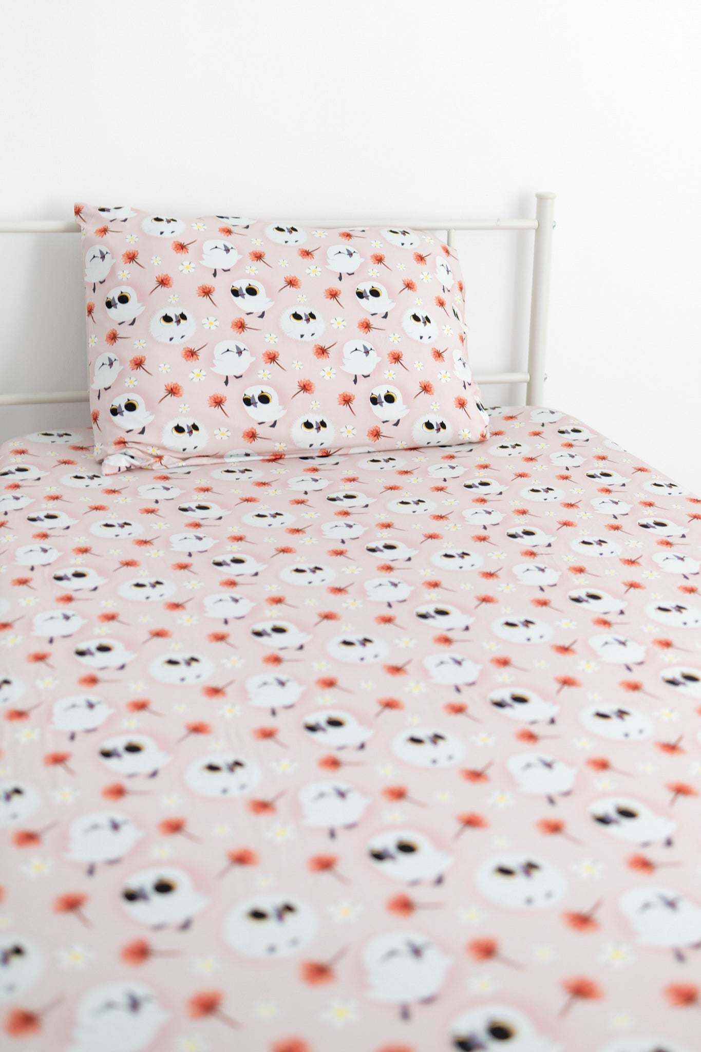 Twin sheet and pillow case set with a pink background and a pattern of white puffins and small flowers.