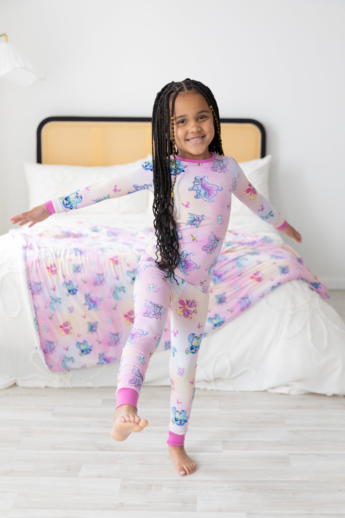 A young girl wears a pink long-sleeve pajama set featuring a Neopets Faerie print.