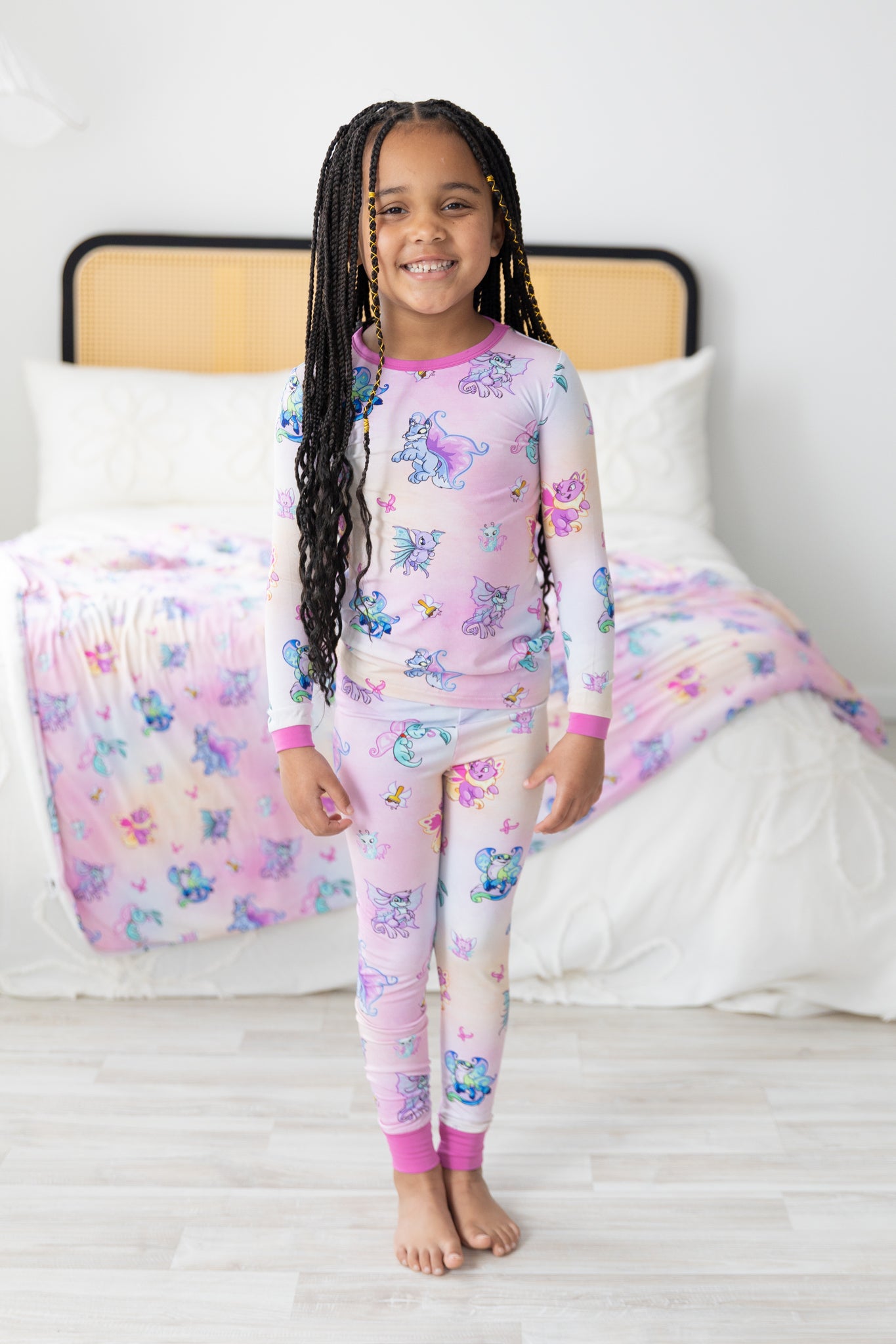 A young girl wears a long-sleeve pajama set featuring a pink and white Neopets Faerie print.