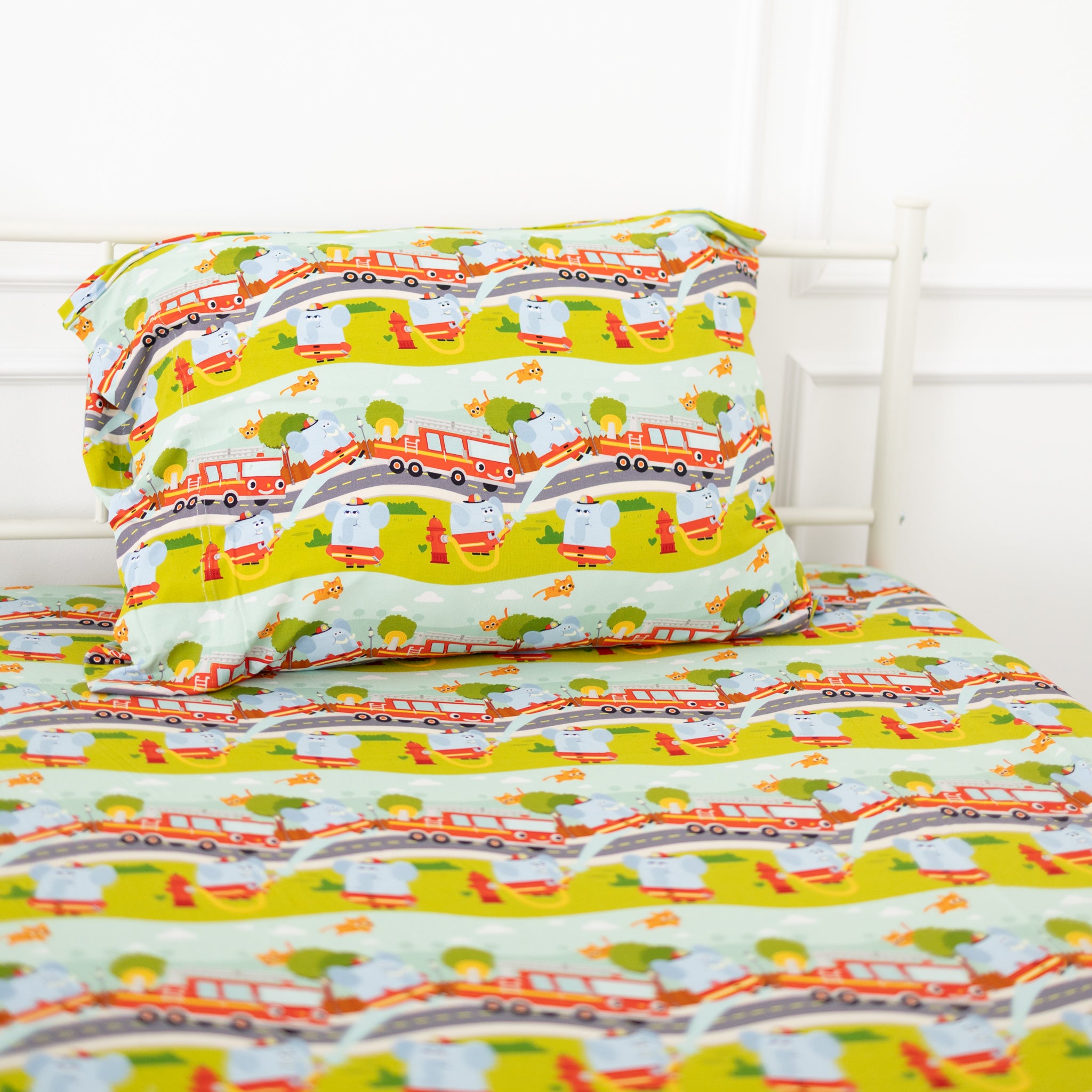 A twin-sized fitted sheet and pillowcase set featuring a colorful firetruck and elephant pattern.