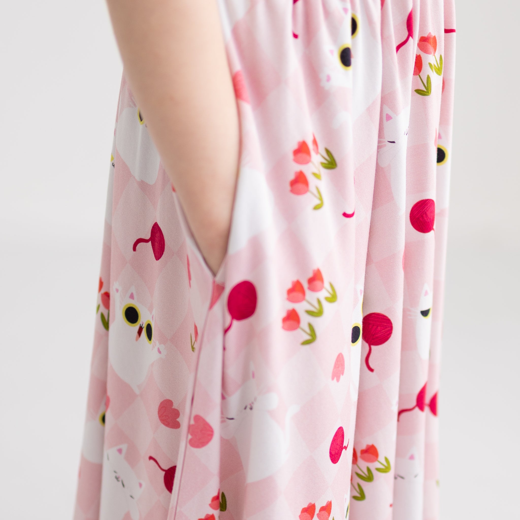 A pink dress with a cat and floral pattern featuring a side pocket.