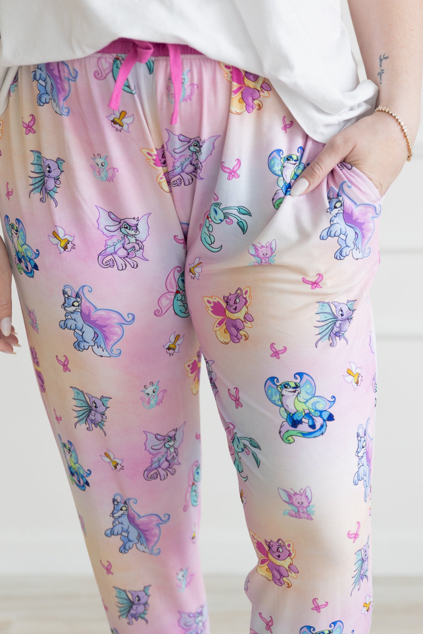 Womens jogger pants in a pink gradient featuring a repeating Neopets Faerie print.