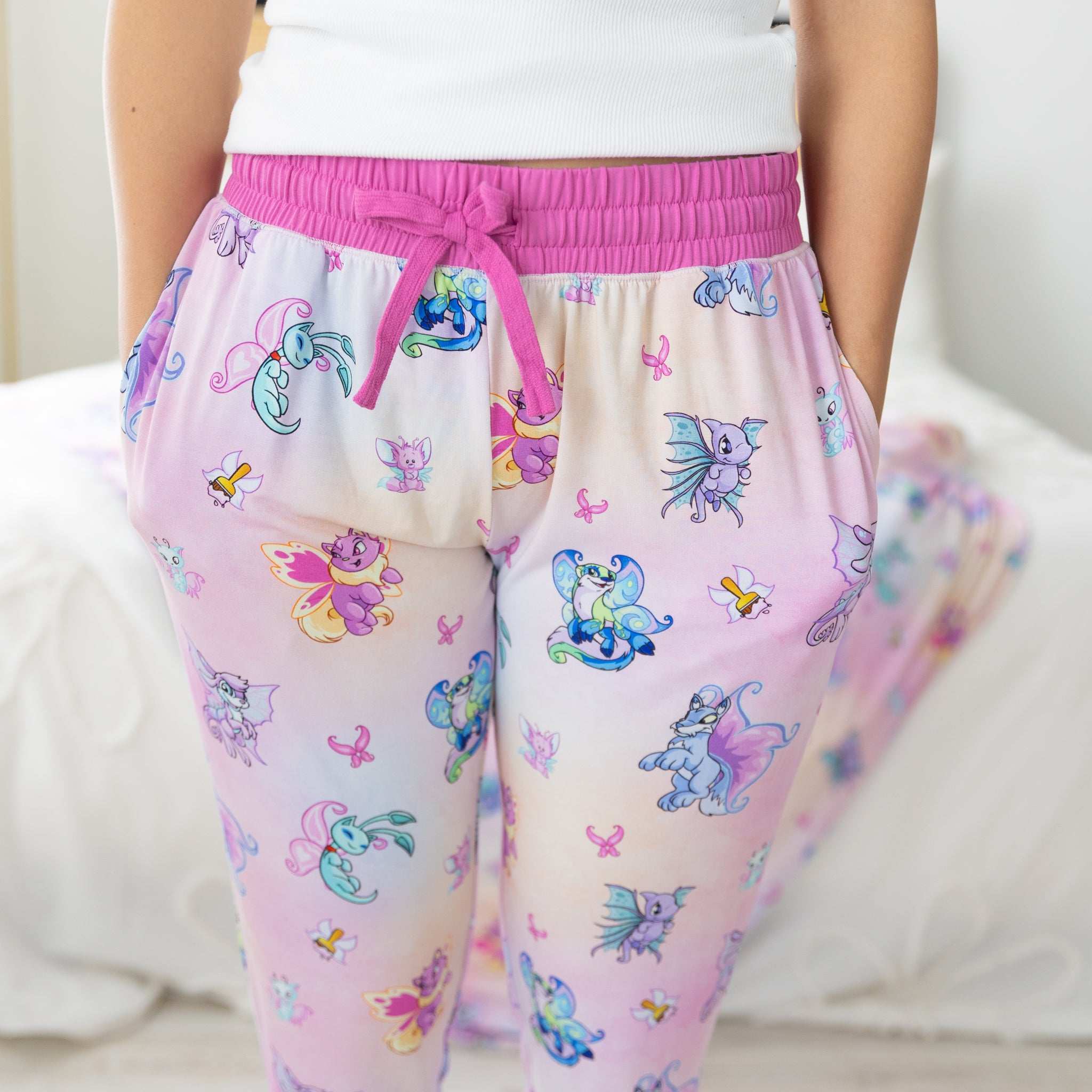 Women's jogger pants featuring a colorful Neopets Faerie print on a pink and white gradient.