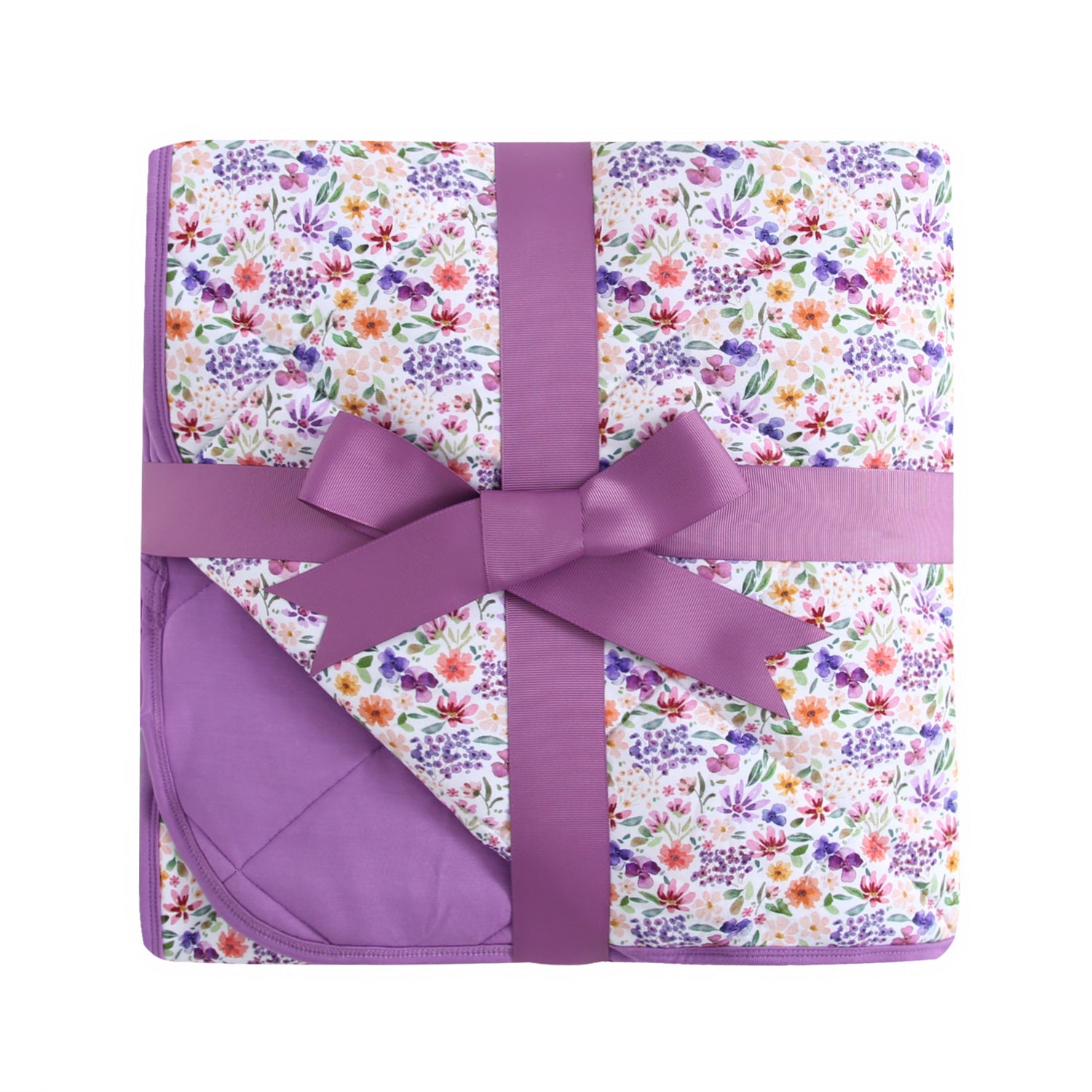 A floral patterned quilt with a purple ribbon tied around it.